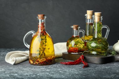 Cooking oil with different spices and herbs in jugs on light grey table