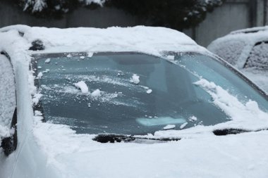 Car windshield with wiper blades cleaned from snow outdoors on winter day clipart