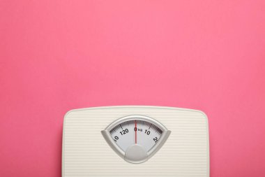 Weigh scales on pink background, top view with space for text. Overweight concept