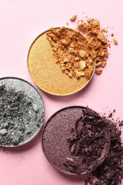 Different crushed eye shadows on pink background, flat lay