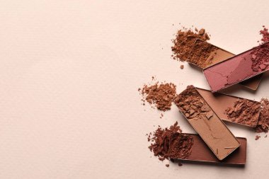 Different crushed eye shadows on beige background, flat lay. Space for text