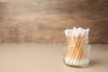Jar of clean cotton buds on beige background. Space for text