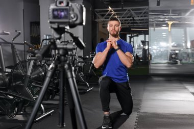 Man recording workout on camera at gym. Online fitness trainer