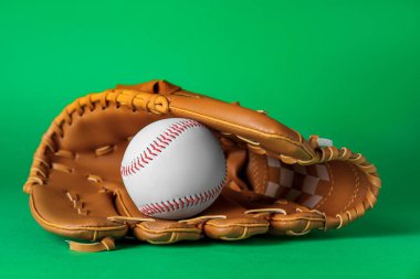 Catcher's mitt and baseball ball on green background. Sports game