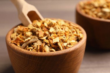 Bowls of dried orange zest seasoning on wooden table, closeup