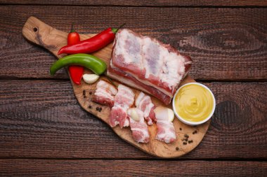 Pieces of pork fatback with chilli pepper and sauce on wooden table, top view