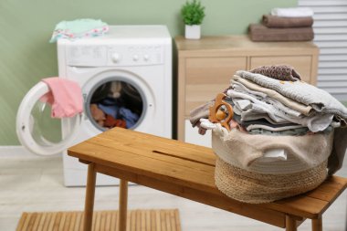 Laundry basket with baby clothes and toy on table in bathroom. Space for text