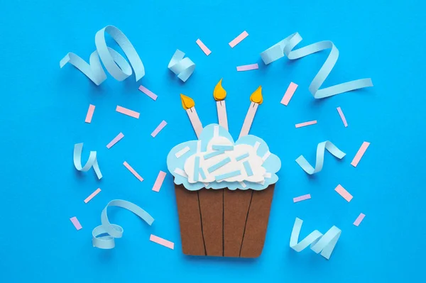 Birthday party. Paper cupcake and confetti on light blue background, flat lay