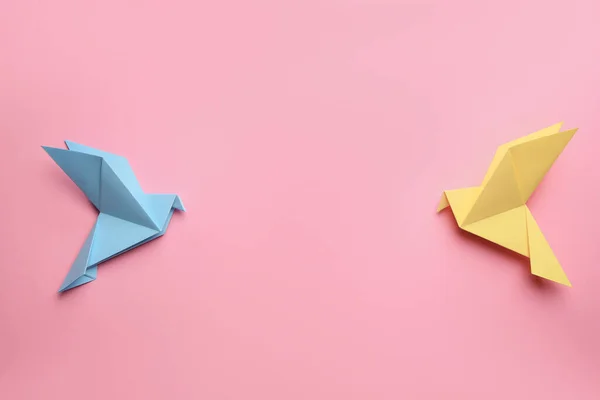 Beautiful colorful origami birds on pink background, flat lay. Space for text