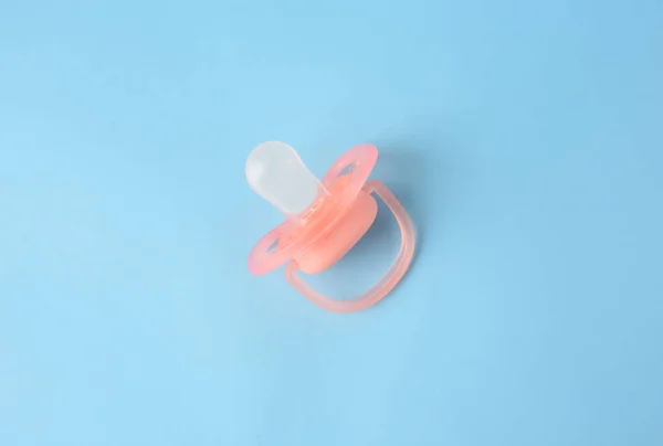 One new baby pacifier on light blue background, top view
