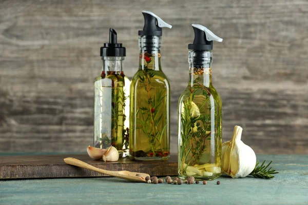 Cooking oil with different spices and herbs in bottles on wooden table