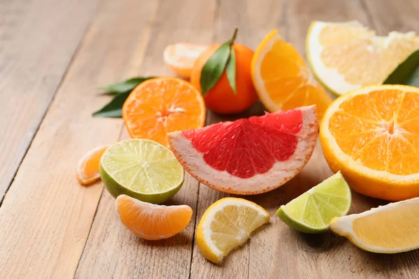 木のテーブルの上に新鮮な葉を持つ異なる柑橘類 — ストック写真