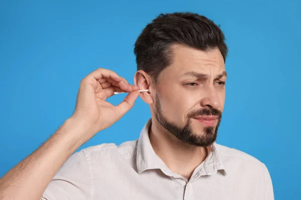 Emotional Man Cleaning Ears Light Blue Background — Fotografia de Stock