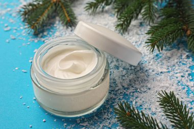 Jar of hand cream and Christmas decor on light blue background. Winter skin care