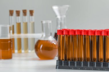 Different laboratory glassware with brown liquids on white table. Space for text