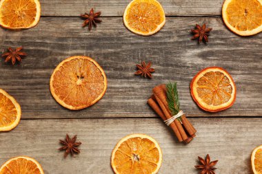 Flat lay composition with dry orange slices, anise stars and cinnamon sticks on wooden table