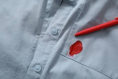 Pen and stain of red ink on light shirt, top view. Space for text
