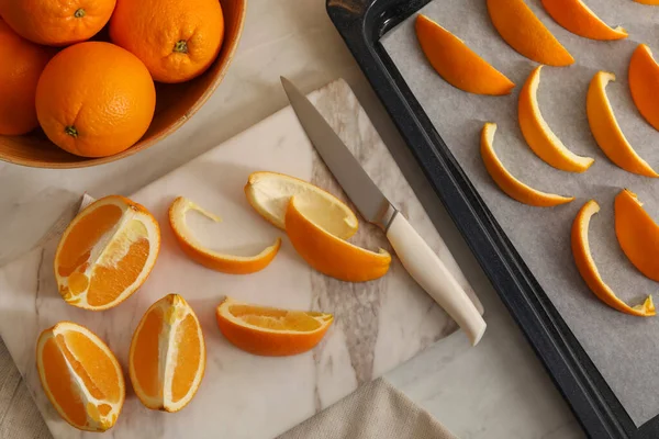 Fresh orange peels and slices of fruits on white table, flat lay