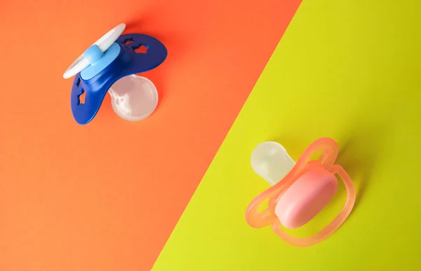 Baby pacifiers on color background, flat lay