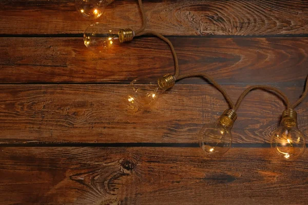 String lights with lamp bulbs on wooden table, top view. Space for text