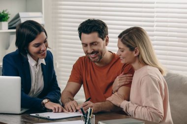Man signing documents at wooden table in notary office