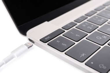 USB cable with lightning connector and laptop on white background