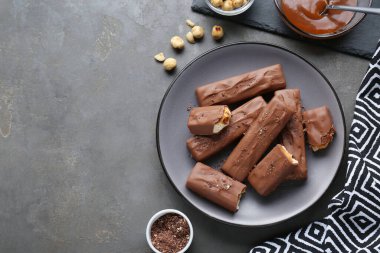 Tasty chocolate bars with caramel and nuts on grey table, flat lay. Space for text