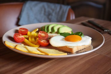 Tasty toasts with fried egg, avocado, cheese and vegetables on wooden table, closeup