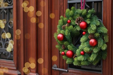 Beautiful Christmas wreath hanging on wooden door, space for text