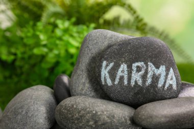 Stone with word Karma on blurred background, closeup. Space for text clipart