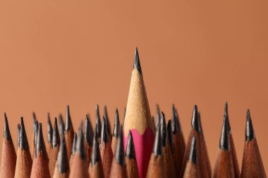 Many sharp graphite pencils on brown background, closeup