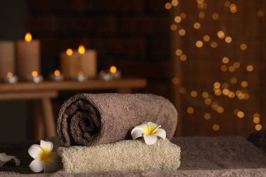 Spa composition with towels and plumeria flowers on massage table in wellness center