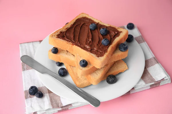 Tasty toast with chocolate paste and blueberries on pink table