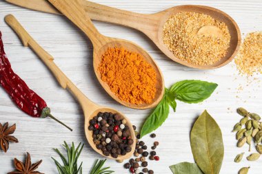 Beyaz ahşap masa üzerinde farklı baharat ve otlarla dolu kaşıklar, düz yatıyordu.