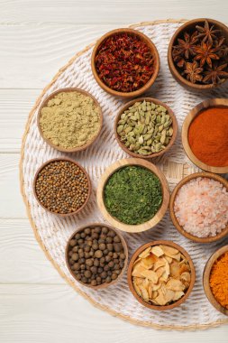 Bowls with different spices on white wooden table, top view