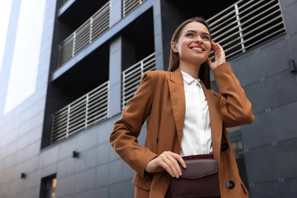 Young woman in formal clothes near building outdoors, space for text