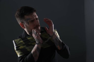 Scared man taped up and taken hostage on dark background. Space for text