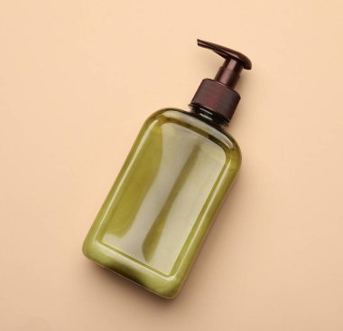 Bottle of shampoo on beige background, top view