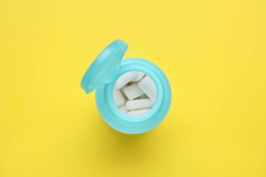 Jar with chewing gums on yellow background, top view