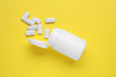 Sarı arka planda sakız çiğneyen kavanoz, düz uzan.