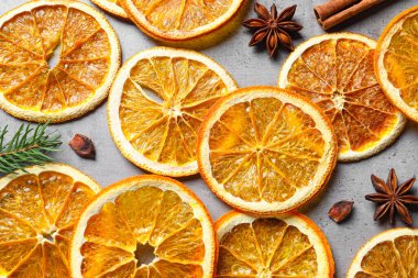 Dry orange slices, cinnamon sticks and anise stars on grey table, flat lay
