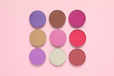 Different beautiful eye shadows on pink background, flat lay