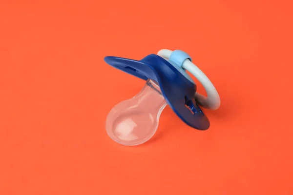 One blue baby pacifier on orange background