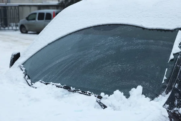 Car windshield with wiper blades cleaned from snow outdoors on winter day
