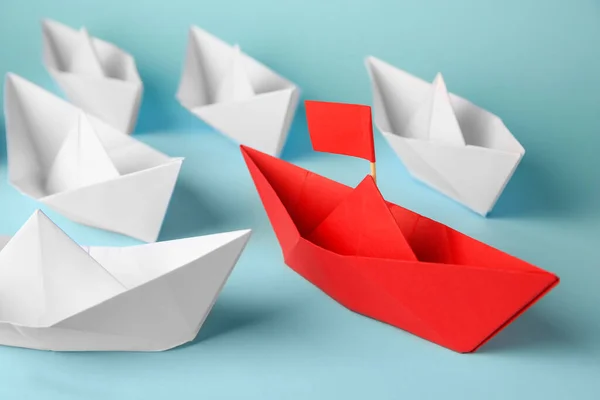 Red paper boat among others on light blue background. Uniqueness concept