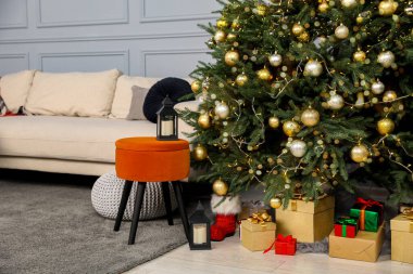 Gift boxes under Christmas tree, ottomans and sofa in living room