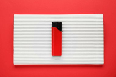 Stylish small pocket lighter with white corrugated fiberboard on red background, top view
