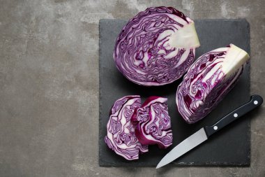 Cut fresh ripe red cabbage and knife on grey table, flat lay. Space for text