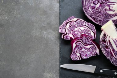 Cut fresh ripe red cabbage and knife on grey table, flat lay. Space for text