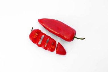 Whole and cut red hot chili peppers on white background, flat lay
